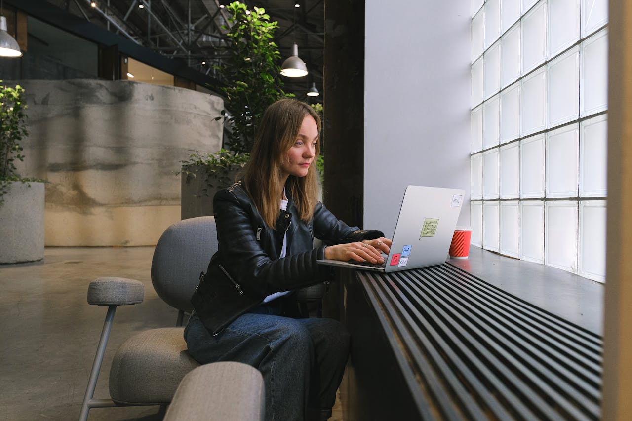 Young woman working on a laptop in a stylish modern office with natural lighting.