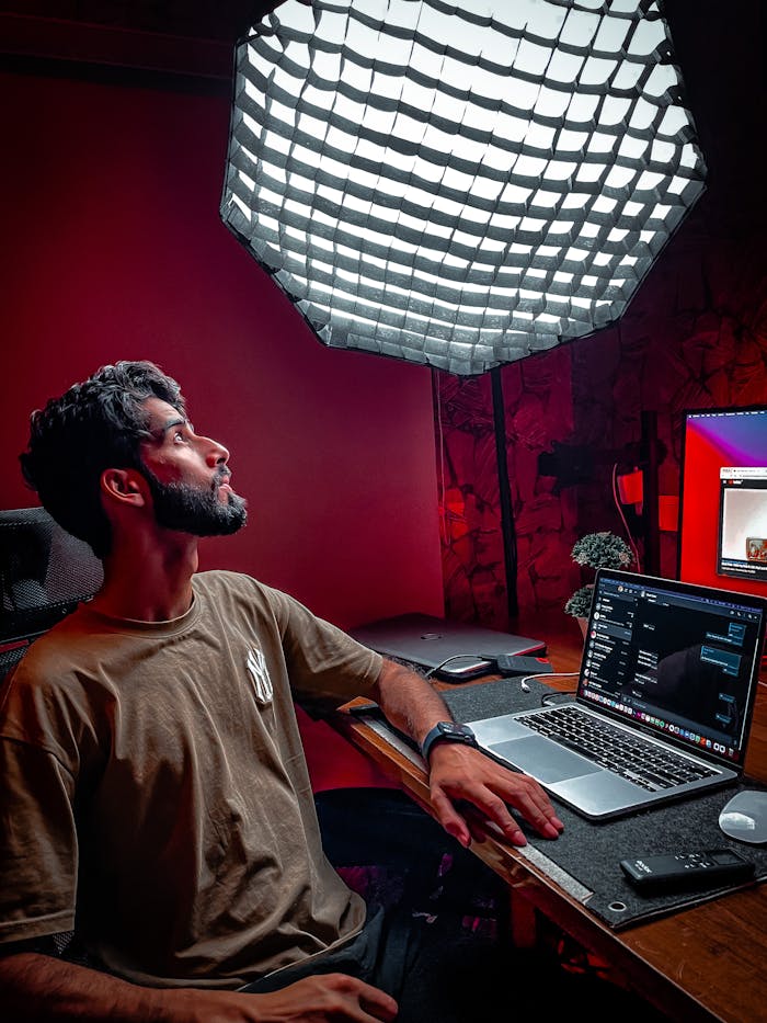 Bearded man freelancing in a modern home office with laptop and spotlight.