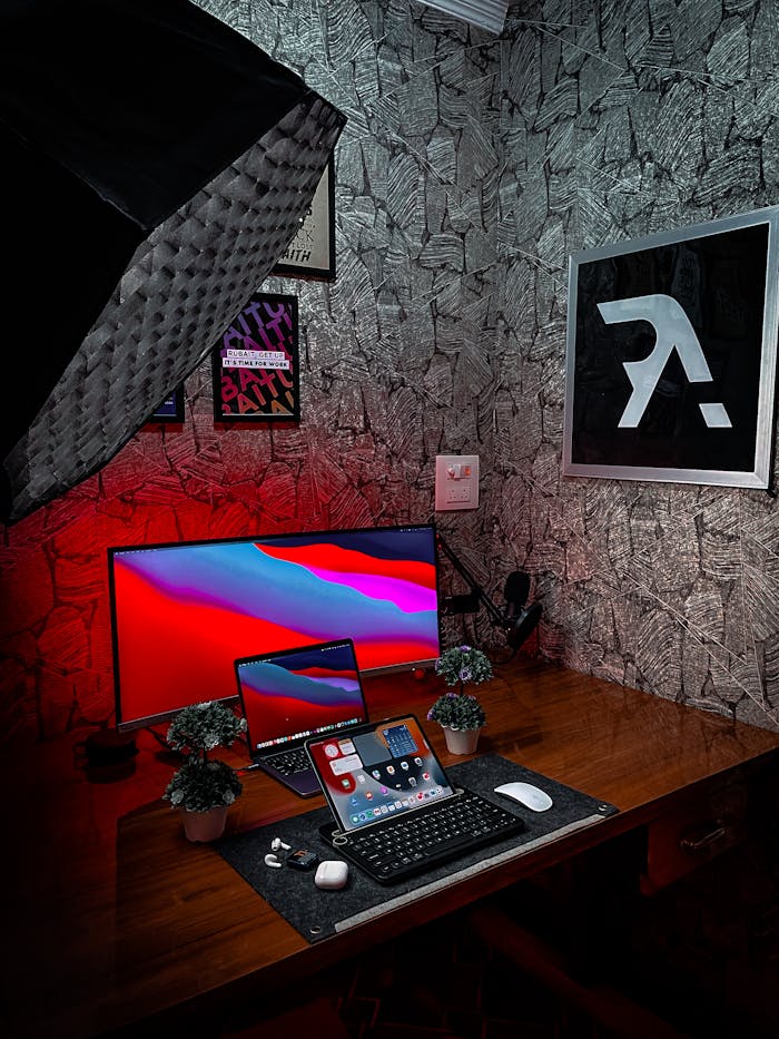 A sleek and tech-heavy home office setup with screens, keyboard, and stylish lighting.